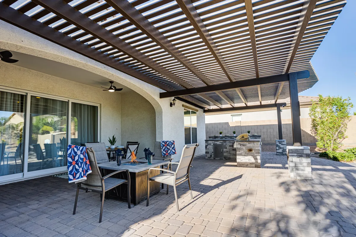 A shaded outdoor dining area with a fully equipped outdoor kitchen, decorative towels, and comfortable seating. The space is ready for family barbecues, relaxed outdoor dining, and casual gatherings.