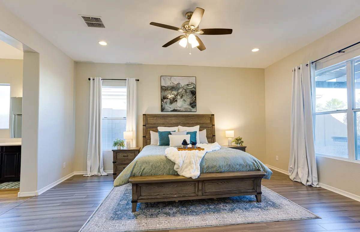 A serene bedroom bathed in natural light, featuring a plush bed with crisp bedding, elegant artwork above the headboard, stylish nightstands with lamps, and a window that invites in gentle morning sun. The atmosphere is peaceful and welcoming, ideal for unwinding after a day of adventure.
